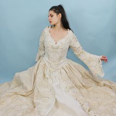 Absolutely INSANE Princess Wedding Dress! Dramatic Ballgown with Bustier Style corset lace up top, long bell sleeves, full skirt, pearl and sequin floral applique, gold shimmery embroidered details, long train, and scalloped lace cutouts. Unbelievable Fairy queen medieval renaissance style look. Size 12, somewhat adjustable with corset. Comes with Matching Rosette GarterBust: 40"-41"Waist: 29"-33"Hips: 82"Length: 56.5"Train: Extra 44" Lace Ball Gown With Intricate Embroidery, Embroidered Ball Gown With Fitted Bodice For Wedding, Wedding Victorian Dress With Boned Bodice, Long Sleeve Wedding Dresses With Boned Bodice, Wedding Ball Gown With Lace Sleeves And Fitted Bodice, Wedding Ball Gown With Lace Trim And Fitted Bodice, Fitted Wedding Ball Gown With Lace Trim, Cream Lace Ball Gown, Victorian Lace Wedding Dress In Marie Antoinette Style