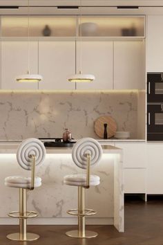 three white bar stools sitting in front of a counter top with lights on it