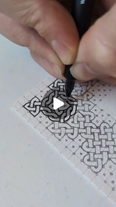 a person is drawing on paper with a pen and inking the design onto it