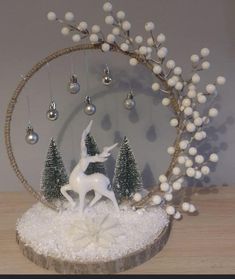 a white deer statue in front of a circular display with christmas trees and balls hanging from it