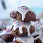 a pile of chocolate donuts with icing and sprinkles on them