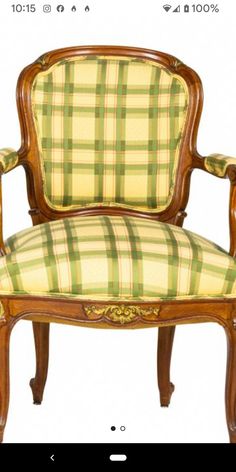 a wooden chair with green and yellow plaid upholstered on the armrests