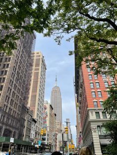 people are walking down the street in front of tall buildings and skyscrapers on a sunny day