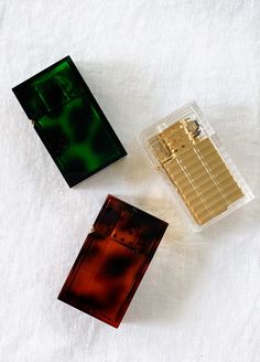 three different types of perfumes sitting next to each other on a white sheeted surface