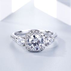 three stone diamond ring on white surface with reflection in the background, close - up