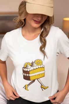 Step into the whimsical world of fashion with our quirky Lemon Cake Walking T-Shirt! This unisex tee features a delightful graphic of a lemon cake slice strutting in high heels, making it the perfect gift for dessert lovers and anyone with a sweet tooth. Crafted from high-quality fabric, this comfortable and stylish shirt is great for casual outings, parties, or as a unique novelty gift. Embrace the fun side of fashion and let your personality shine with this charming and humorous design. We uti Sweet White T-shirt With Funny Print, White Sweet T-shirt With Funny Print, Sweet White T-shirt With Graphic Print, Sweet Cartoon Print Crew Neck T-shirt, Sweet Style Crew Neck T-shirt With Cartoon Print, Heels Unique, Cake Walk, Novelty Shirts, Cake Slice