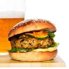 a hamburger with lettuce and carrots next to a glass of beer