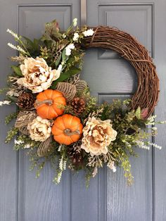 a wreath with flowers and pumpkins on the front door