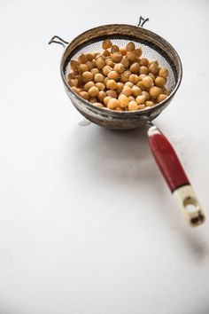 a metal strainer filled with chickpeas sitting on top of a white table