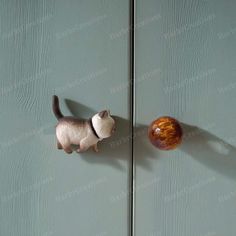 a cat figurine standing next to an apple on a green door with shadow