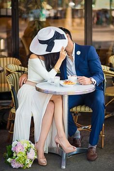 a man and woman sitting at a table in front of each other with hats on