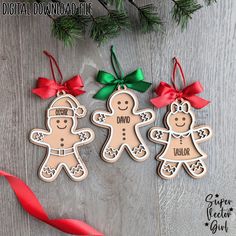 three gingerbread cutout ornaments with bows and ribbons on a wooden table next to red ribbon