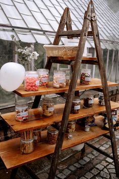 an old ladder is used as a shelf for jars and other items to store on