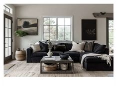 a living room with black couches and white rugs on the wooden flooring