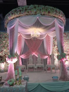 an elaborately decorated wedding stage with pink and white draping, chandelier and flowers