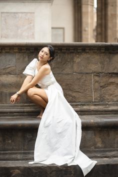 a woman in a white dress sitting on some steps