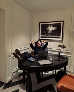 a woman sitting at a table with a laptop in front of her, holding her head