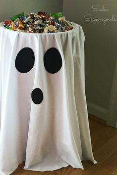 a table that has some candy in it and is decorated like a ghost with black polka dots