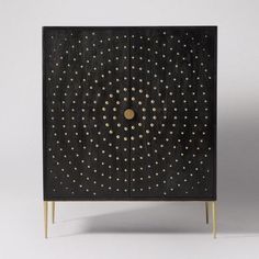 a black cabinet with gold dots on the front and bottom, against a white background