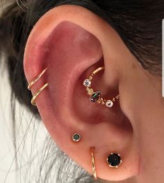 an ear with three different types of piercings on top of it, and one in the middle