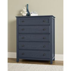 a blue chest of drawers in a room with a rug and vase on the floor