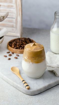 a glass jar filled with white and brown liquid sitting on top of a counter next to coffee beans