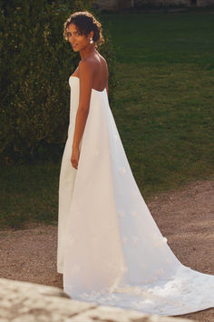 a woman in a white wedding dress standing outside