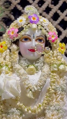 a close up of a statue of a person with flowers on her head and face