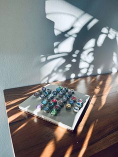 a white plate topped with lots of different colored glass knobs on top of a wooden table