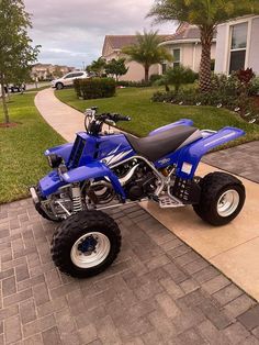 a blue four - wheeler parked on the side of a sidewalk next to a house