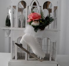 a pair of ice skates decorated with flowers and feathers in front of a white birdcage