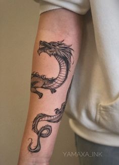 a woman's arm with a dragon tattoo on the left side of her arm