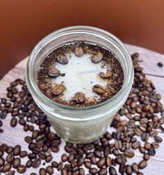 a glass jar filled with coffee beans on top of a wooden table covered in dirt