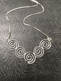 I like spirals and in Celtic lore, they can represent going from stages of oneself primal points to enlightenment, and though most of us have a way to go, we can at least adorn one in hopes of always continuing on a path of growth and self-reflection. This Celtic Spiral Necklace, in sterling silver, with each scroll hand-made in alternating plain and twist 16 gauge wire, embodies Celtic symbolism. I wanted to fabricate something meaningful and magical within the spirit of these ancient symbols. Artistic Handmade Swirl Jewelry, Unique Spiral Sterling Silver Necklace, Silver Spiral Bohemian Necklace, Spiral Wire Wrapped Sterling Silver Necklace, Artistic Spiral Wire Wrapped Jewelry, Artistic Wire Wrapped Spiral Jewelry, Handmade Spiral Silver Necklace, Unique Silver Spiral Necklace, Bohemian Silver Spiral Necklace