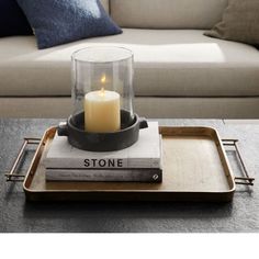 a tray with a candle on top of some books and a couch in the background