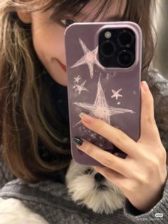 a woman holding up her phone case with stars on it