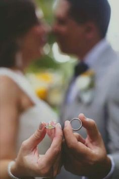 a bride and groom holding their wedding rings