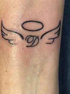 a small tattoo on the arm of a person with an angel wing and halo around it