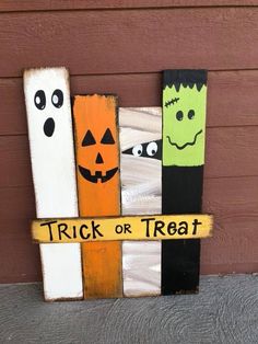 a wooden sign that says trick or treat with two pumpkins and ghost faces on it