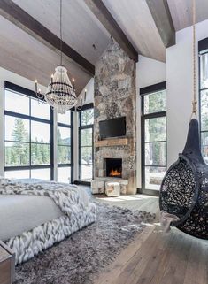 a bedroom with stone fireplace and large windows