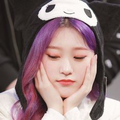 a girl with purple hair wearing a panda hat and holding her hands to her face