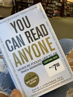 the book you can read anyone is in someone's lap with ripped jeans on