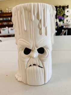 a white vase with a face made out of wood