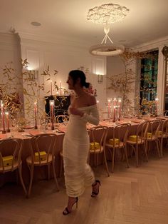 a woman in a white dress standing next to a table