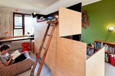 there is a boy reading on the floor in his room with bunk bed and bookshelf