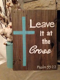 a wooden sign with the words leave it at the cross on it and some cotton flowers