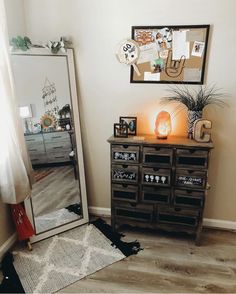 a room with a mirror, dresser and lamp on the floor in front of it