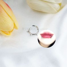 a close up of a ring on a white surface with flowers in the back ground