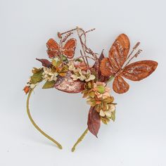 a headband with flowers, leaves and butterflies on it's side against a white background