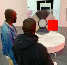 two men standing in front of a display with a cd on it's stand